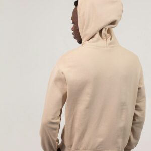 Back view of African American man in hoodie and sweatpants standing with hands in pockets against white background